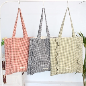 Vue détaillée de sacs cabas à carreaux rouges, noirs et verts avec bords à volants
