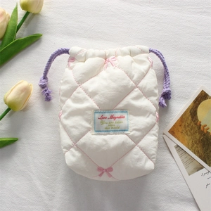 Detail of white quilted camera pouch with pink bow embroidery and purple drawstrings