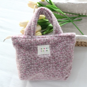 Detailed close-up of pink leopard print plush handbag with soft faux fur texture and tag