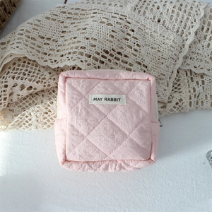 Close-up of pink quilted mini cosmetic pouch with May Rabbit label and zipper detail