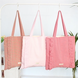 Détail des sacs cabas en toile à volants avec motifs à carreaux et étiquettes en tissu