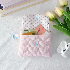 Detailed close-up of pink quilted heart pouch with blue snap and red polka dot lining