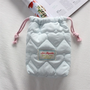 Detail of light blue quilted heart camera pouch with pink drawstring and soft fabric