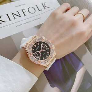 Detail of rose gold quartz watch with rhinestone bezel and white silicone strap on wrist