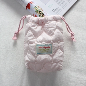 Close-up of pink quilted cotton camera bag with heart embroidery and drawstring closure