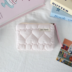 Close-up of pink quilted coin purse with heart patterns and May Rabbit fabric label