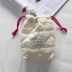 Close-up of quilted cream camera pouch featuring pink drawstrings and heart patterns