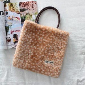 Detail shot of plush deer print tote bag featuring a leather handle and brand woven label