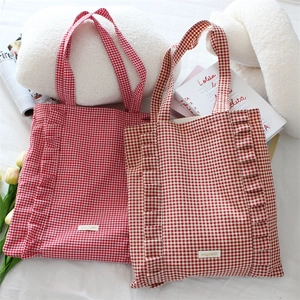 Détail du sac cabas en toile à carreaux avec bords à volants et étiquette de marque