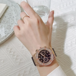 Close-up of a luxury women's watch with rhinestones and black silicone strap on wrist