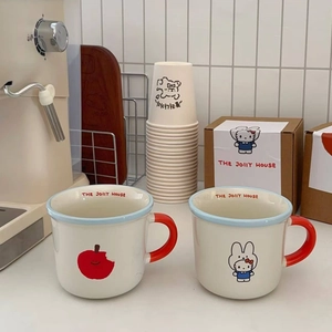 Close-up of Japanese style ceramic mugs featuring apple and cat illustrations in gift box