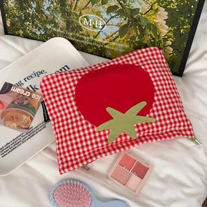 Makroaufnahme einer rot-karierten Kosmetiktasche mit Tomatenstickerei auf Leinen