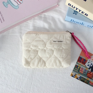 Macro shot of quilted heart pattern and pink cord on a cream mini storage bag
