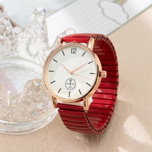 Détail d'une montre à quartz or rose avec bracelet élastique rouge et présentoir couronne