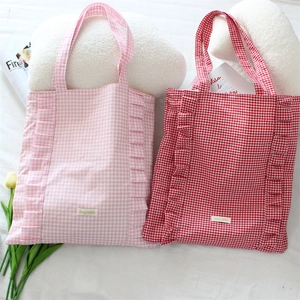 Détail de sacs fourre-tout à carreaux avec bords à volants en rose et rouge, style mignon