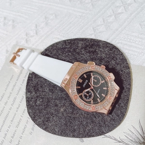 Detail of rose gold diamond bezel watch with black dial and white silicone strap