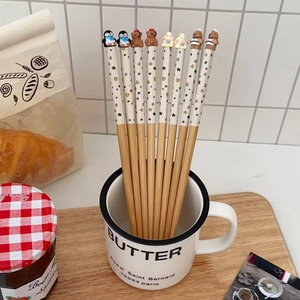 Dettaglio di bacchette in legno con figure di animali in una tazza bianca di casa