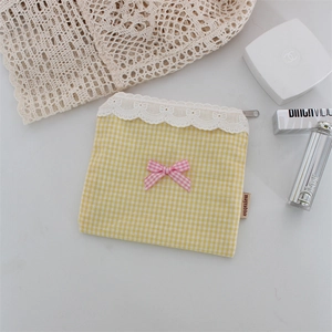 Dettaglio della pochette a quadretti gialli con pizzo, fiocco rosa e cerniera
