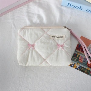 Macro detail of white quilted coin purse with pink bow and MAY RABBIT woven brand label