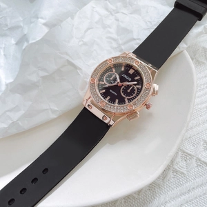 Detailed close-up of rose gold rhinestone bezel and black silicone strap on men's quartz watch