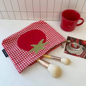 Detail der rot karierten Tomaten-Kosmetiktasche mit Textur und Make-up-Pinseln