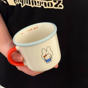 Detail of a ceramic Miffy mug with Hello Kitty bow and a bold orange handle