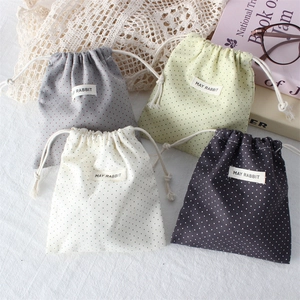 Detailed set of four mini drawstring bags in polka dot linen fabric with logo tags
