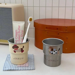 Detail of stainless steel dachshund mugs with cute dog prints in a cozy home bathroom setting