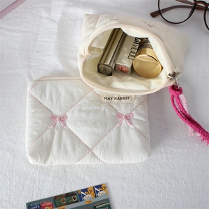 Detailed macro view of quilted makeup bag set featuring pink bow embroidery and tassel
