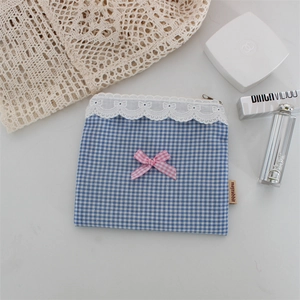 Dettaglio borsa cosmetica a quadretti blu con pizzo bianco e fiocco rosa