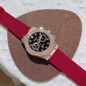 Close-up of JINGIS quartz watch with rose gold diamond bezel and red silicone strap