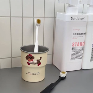 Detail of a beige dachshund cartoon mouthwash cup with a white toothbrush in a cozy bathroom