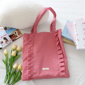 Détail du sac cabas à carreaux rouges avec bords à volants et étiquette tissée