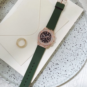 Detail of rose gold watch case with crystal bezel and dark green silicone strap