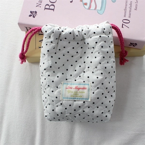 Detail of white quilted heart pattern camera pouch with black dots and pink drawstring