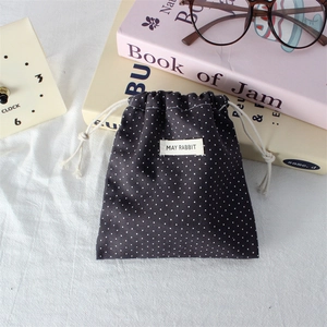 Detailed view of grey polka dot drawstring pouch with May Rabbit label on white surface