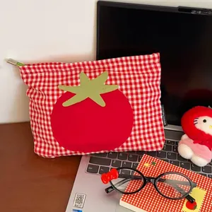 Detailaufnahme der rot karierten Kosmetiktasche mit Tomaten-Patch auf Schreibtisch
