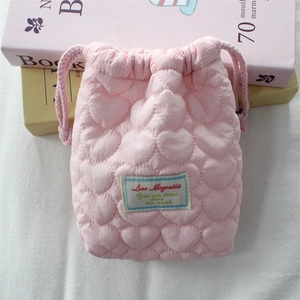 Close-up of pink quilted camera bag featuring heart patterns and soft drawstring closure