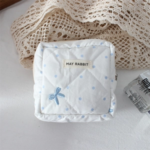 Detailed close-up of quilted cotton storage bag with blue polka dots and bow embroidery