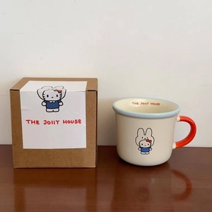 Detail of a ceramic mug with red handle and cartoon character beside its gift box