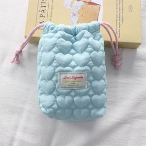 Macro shot of light blue heart-quilted camera pouch with pink drawstrings and soft texture