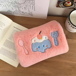 Detail of pink plush electric hot water bag with cute blue monster embroidery on table