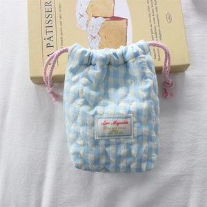 Detailed view of blue gingham quilted camera pouch with pink drawstring and heart pattern