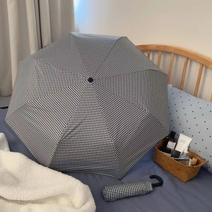 Detailed view of checkered sun umbrella with matching sleeve on a cozy bed background