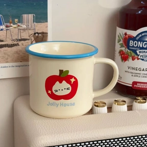 Close-up of ceramic mug with red apple pattern and blue rim in a cozy setting