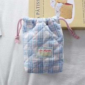Detailed view of quilted plaid camera pouch with soft padded texture and drawstring closure