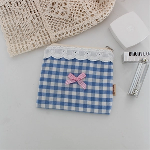 Dettaglio di pochette a quadri blu con bordo in pizzo bianco e fiocco rosa