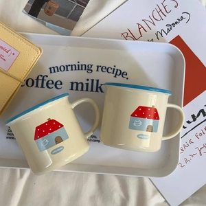 Close-up of ceramic mugs with cat and house illustrations and smooth ergonomic handles