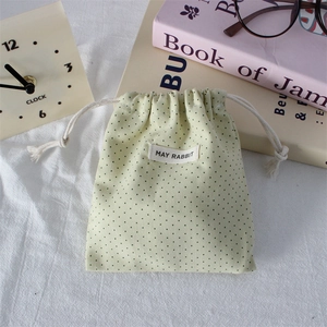 Detail of polka dot drawstring bag with May Rabbit label on a vintage desk