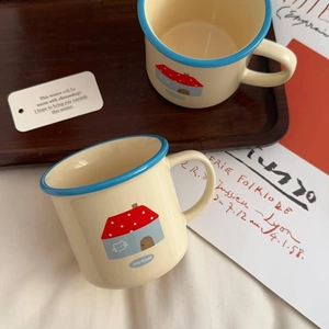 Detail of cream ceramic mugs with blue rim and house motif on a dark wooden tray
